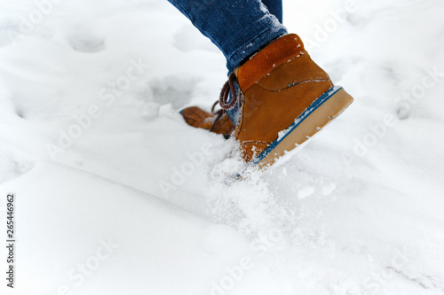 Legs of woman walking in winter park. Girl boots walking snow weather. Closeup of winter shoes