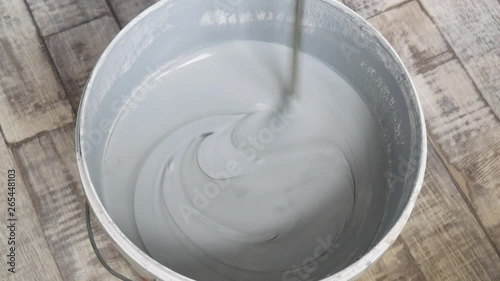 Bucket with water-emulsion paint, stirred with a stirrer. photo