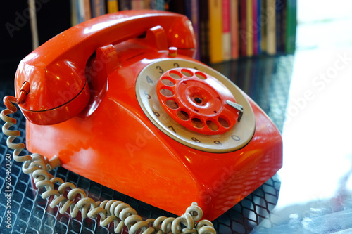 Closeup old fashioned fixed line orange rotary phone on glass table photo