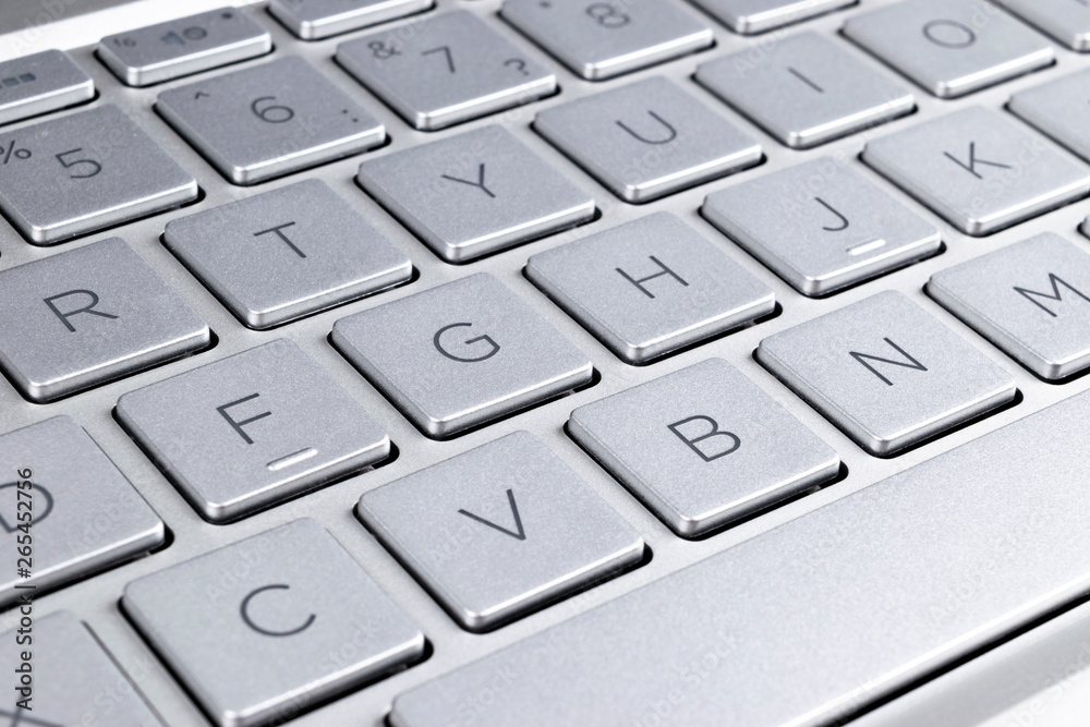 Closeup of a modern silver laptop computer keyboard. Laptop keyboard. Detail of the new and ergonomic computer keyboard.