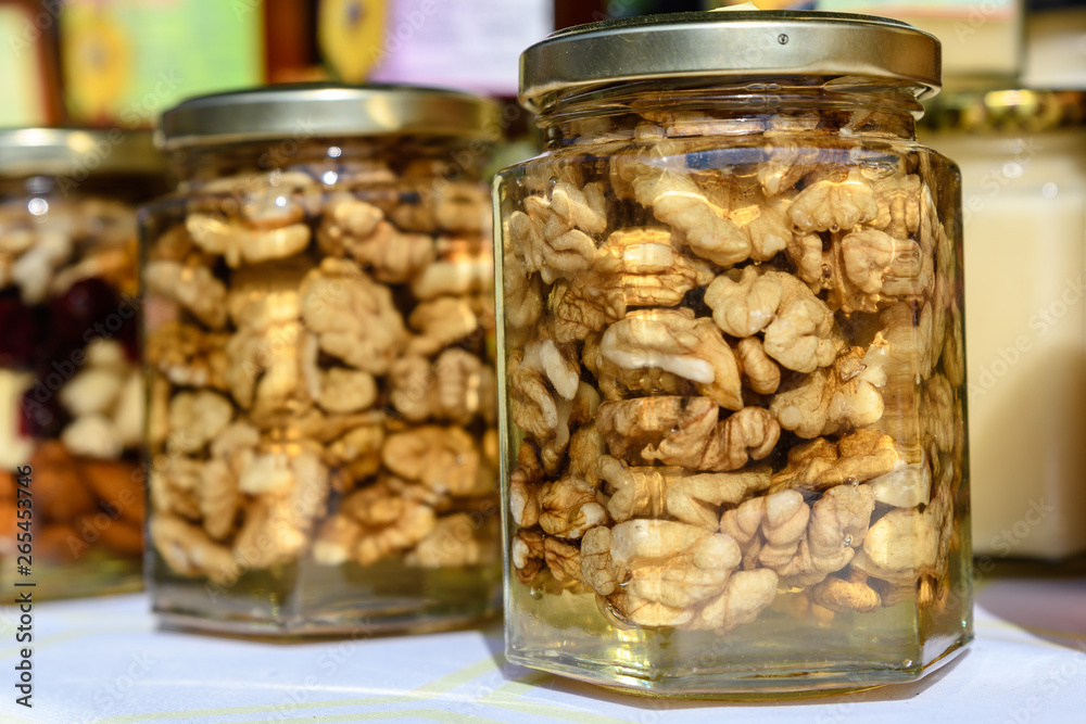 Close up of a jars with honey and walnut kernels in direct sunlight, available for sale at a street food market Close up of a jars with honey and walnut kernels in direct sunlight, available for sale at a street food market