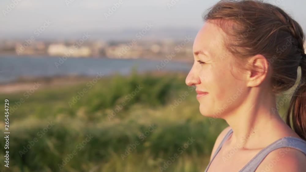 Sporty young woman enjoying a beautiful view of the sea. She inhales the sea air and opens her eyes. Sporty young woman enjoying a beautiful view of the sea. She inhales the sea air and opens her eyes.