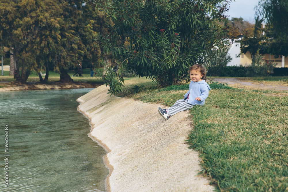 Fototapeta premium Baby girl alone outside in a green park Valencia