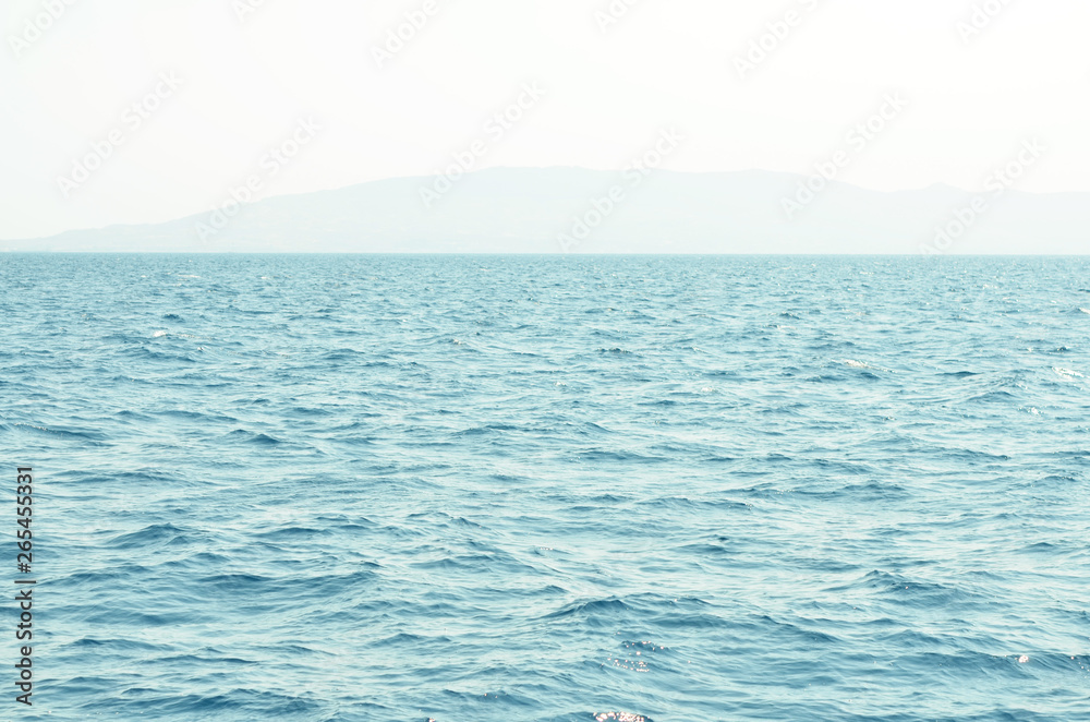 Obraz premium Sea water surface and waves stretch out to the horizon where islands are visible far away.
