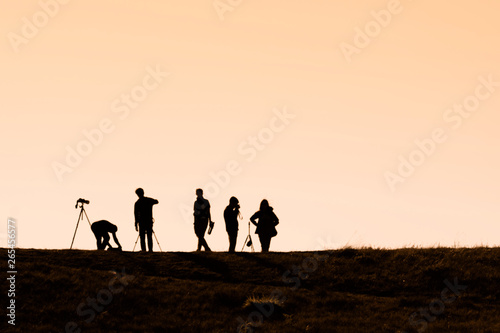 Silhouettes of hikers with backpacks enjoying sunset view from top of a mountain