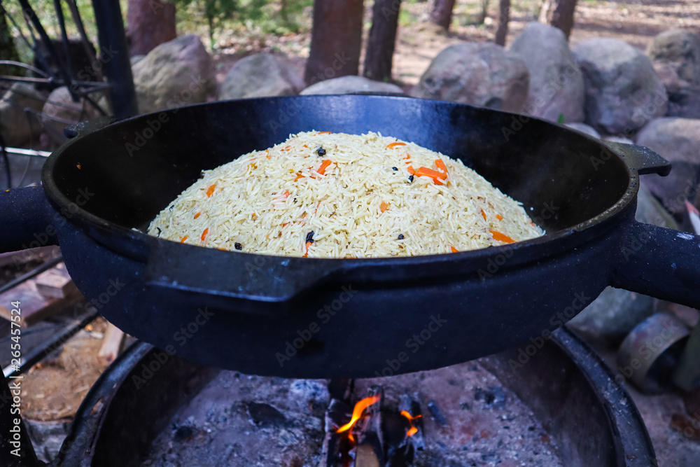 Rice pilaf in a large cast-iron cauldron on fire Rice pilaf in a large cast-iron cauldron on fire
