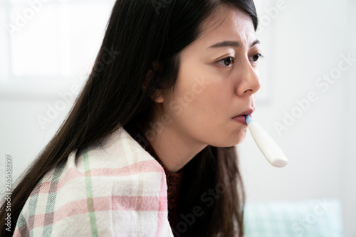 woman wrapped blanket with thermometer in mouth