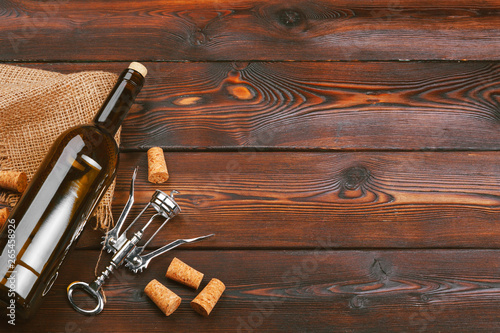 Bottle of wine and cork and corkscrew on wooden table