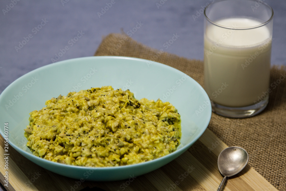 bowl of oatmeal with cinnamon and poppy seeds on a wooden table. A glass of kefir, biscuit. oatmeal bowl of oatmeal with cinnamon and poppy seeds on a wooden table. A glass of kefir, biscuit. oatmeal