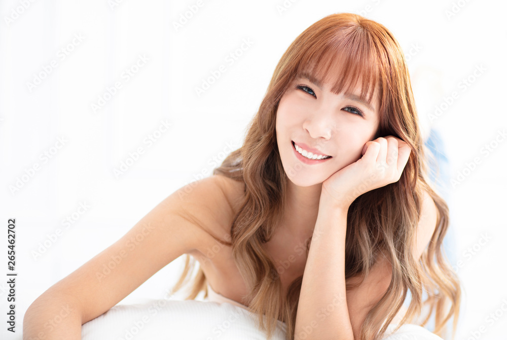 young woman smiling and lying on bed young woman smiling and lying on bed