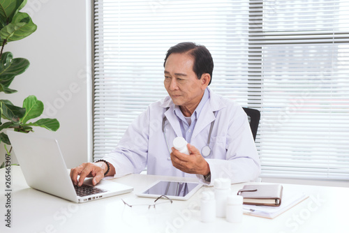 Portrait of senior doctor sitting at his desk in medical office
