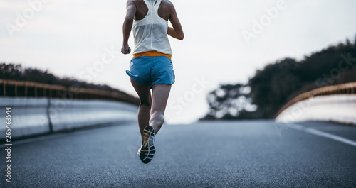 Young fitness woman running on city road