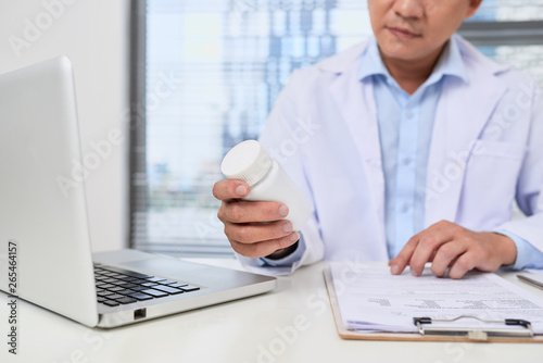 male doctor holding a box of pills in medical office