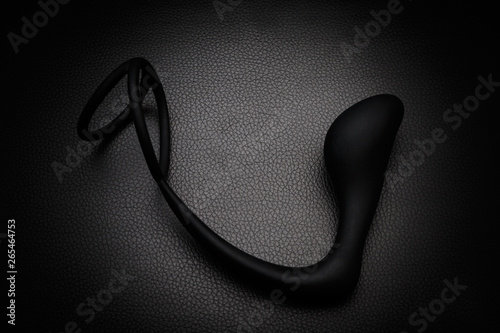 Black silicone prostate massager on black leather. Anal plug.
