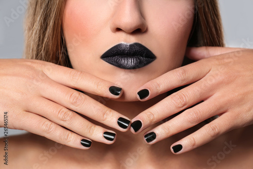 Beautiful woman with stylish nail polish on grey background, closeup