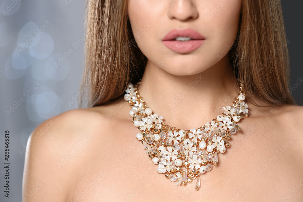 Beautiful woman with stylish jewelry against blurred lights, closeup