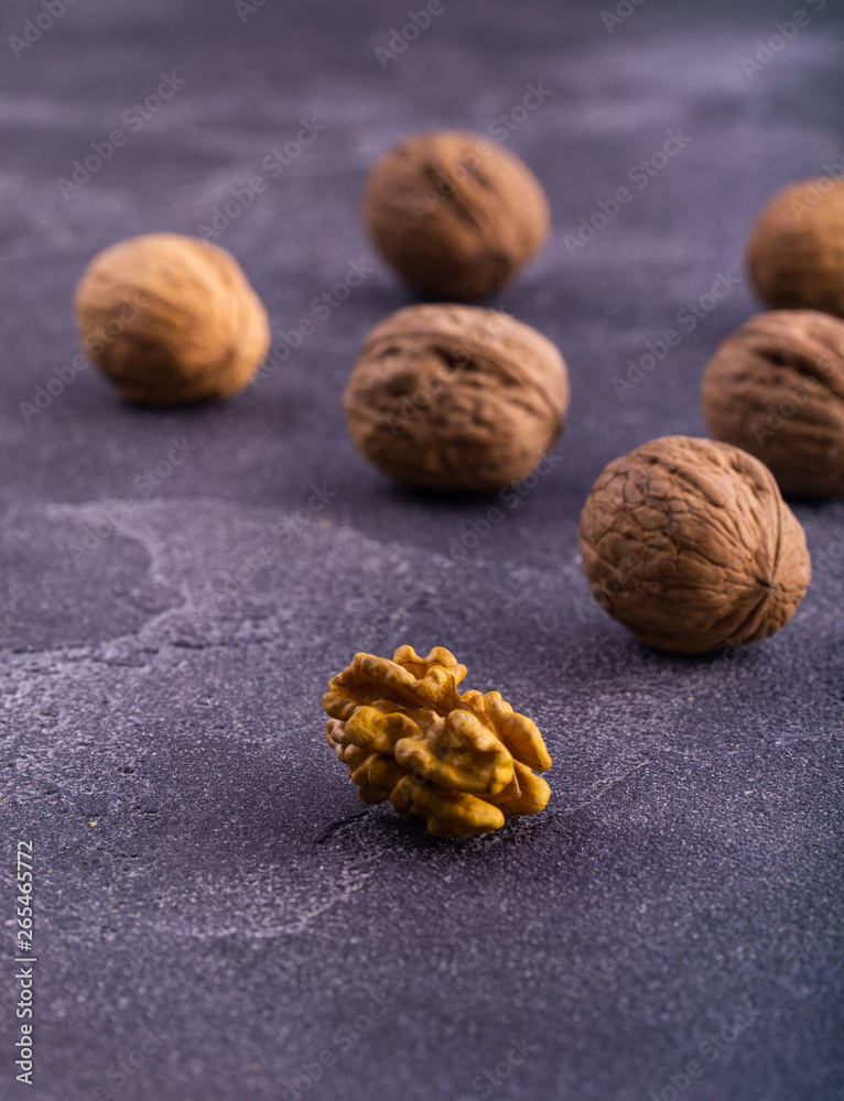 Whole and cracked walnuts on blue textured surface, side view. Healthy nuts and seeds. Whole and cracked walnuts on blue textured surface, side view. Healthy nuts and seeds.
