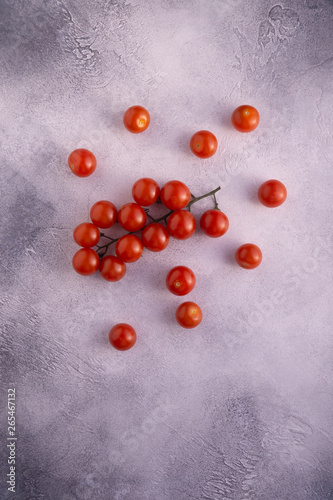 Bunch of cherry tomatoes on white textured stone concrete table, top view with copy space. Ingredients for cooking.