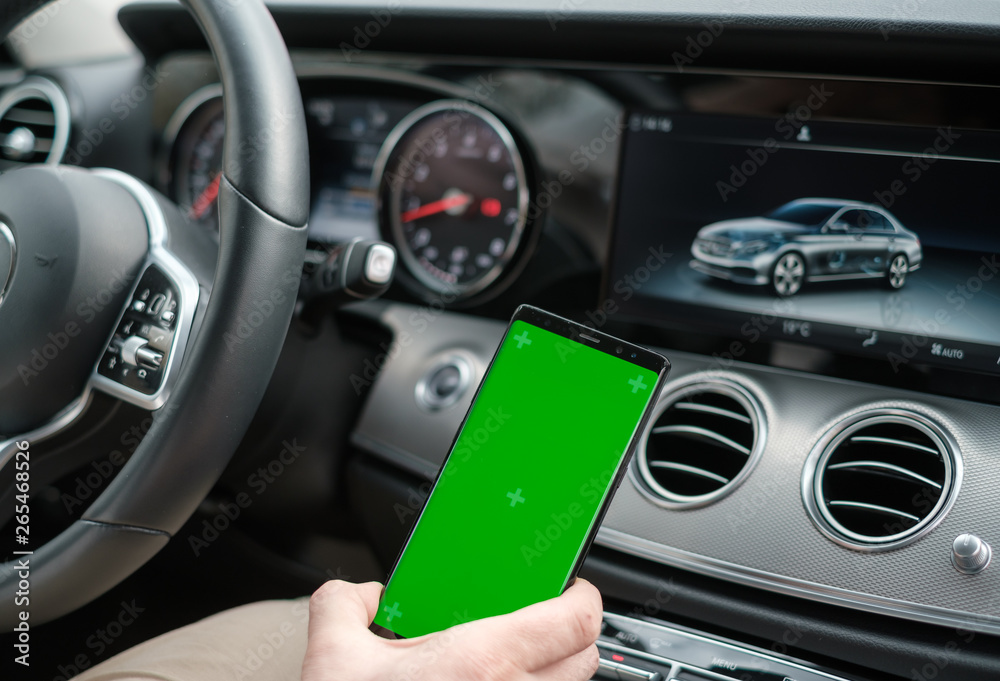 Man using smartphone on the background of a luxury class car dashboard Man using smartphone on the background of a luxury class car dashboard