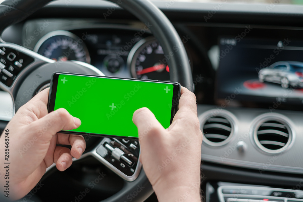 Man using smartphone on the background of a luxury class car dashboard Man using smartphone on the background of a luxury class car dashboard