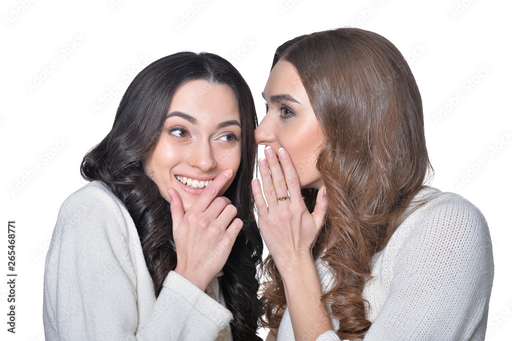 Close-up portrait of two female friends sharing secrets isolated Close-up portrait of two female friends sharing secrets isolated