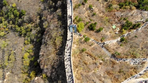 Drone shot following crowded great wall of china. Many people during high season in the Beijing wonder of the modern world. Tourist area packed with crowds on tours. Popular travel destination.
