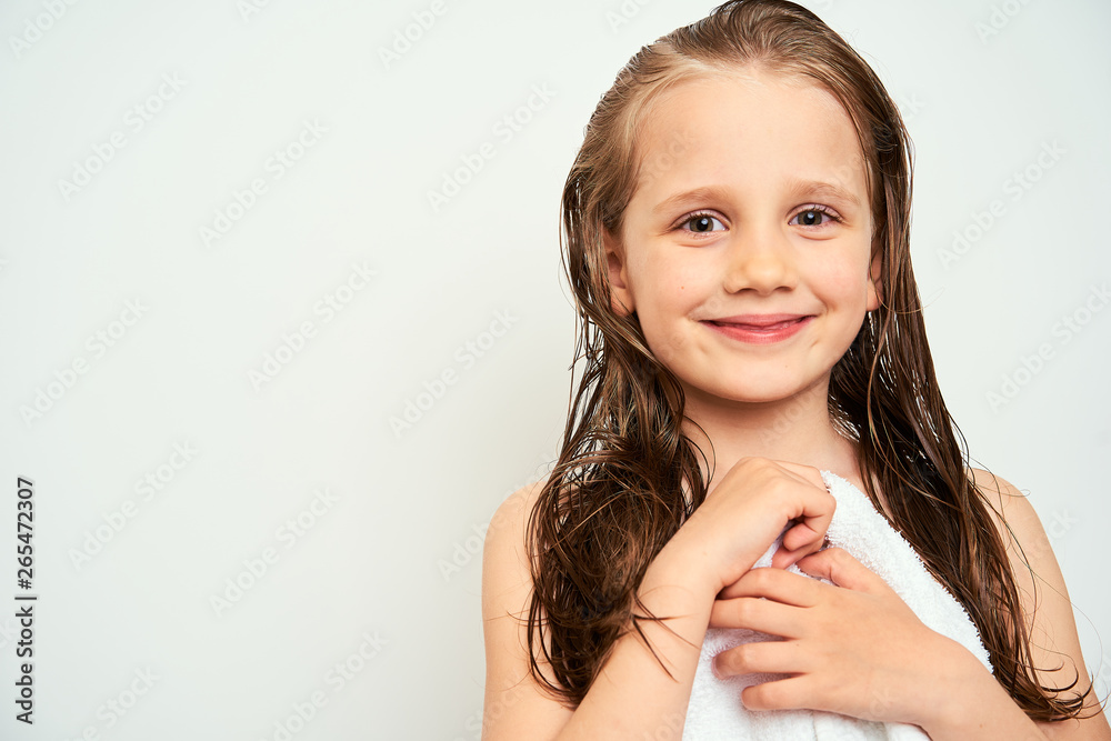 Smiling little preschool girl with wet hair photographed against white background wrapped in white towel Smiling little preschool girl with wet hair photographed against white background wrapped in white towel