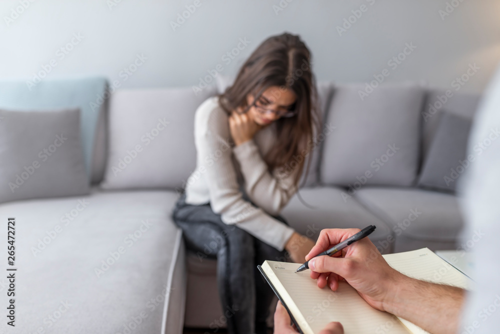 Cropped image of depressed man at the psychotherapist. Doctor is making notes while listening to his patient. Woman at therapy session. Attentive psychologist. Cropped image of depressed man at the psychotherapist. Doctor is making notes while listening to his patient. Woman at therapy session. Attentive psychologist.