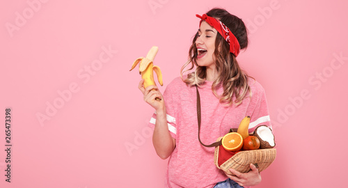 Portrait of a girl with healthy food, fruits, on a pink background