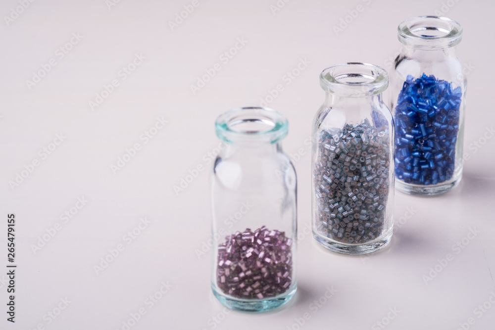 Varied colors beads in transparent bottles white background