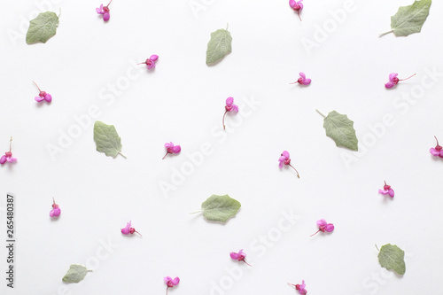 Spring pink flowers and light green young leaves on texture white paper. Spring background for design and decoration.