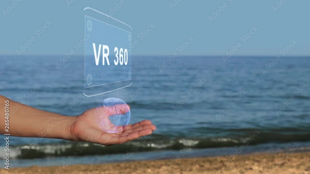 Male hands on the beach hold a conceptual hologram with the text VR 360. A man with a holographic technology on the background of the sea Male hands on the beach hold a conceptual hologram with the text VR 360. A man with a holographic technology on the background of the sea