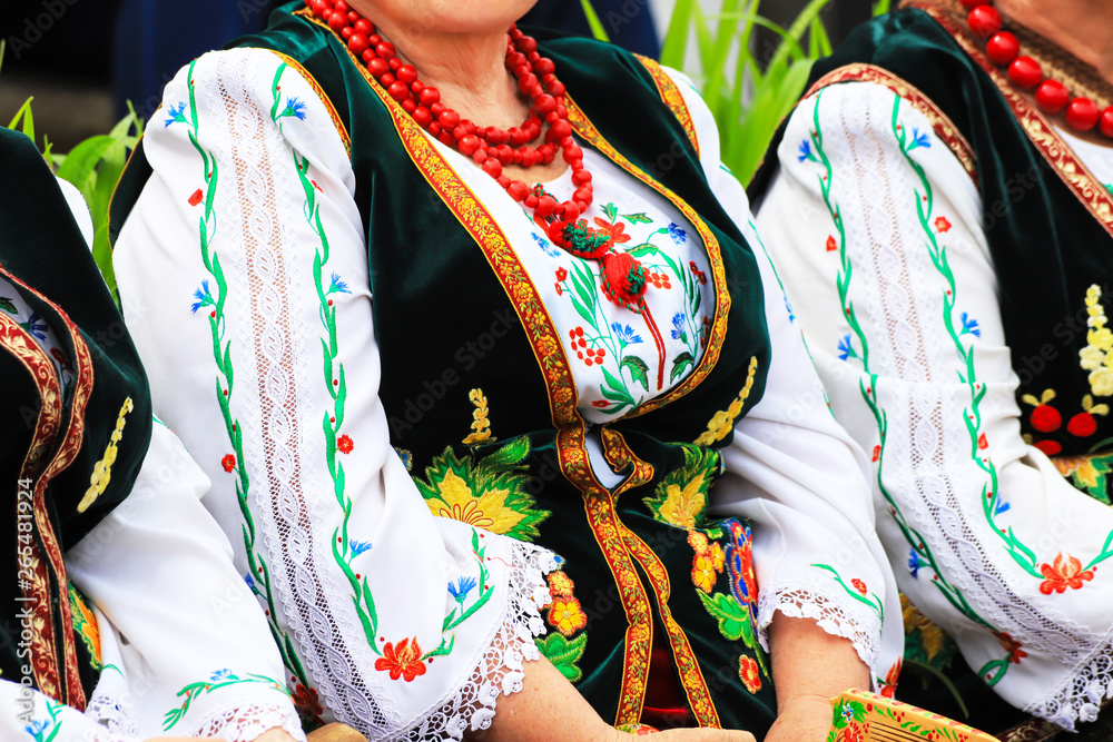 Elderly woman in traditional national  Ukrainian costume, embroidered blouse, embroidery, waistcoat and beads, detail, close-up. Ukraine