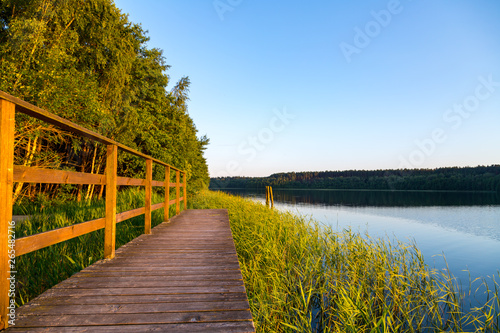 ein See mit Holzsteg umgeben von Wald 