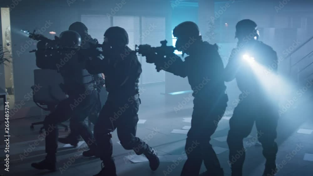 Masked Team of Armed SWAT Police Officers Slowly Move in a Hall of a Dark Seized Office Building with Desks and Computers. Soldiers with Rifles and Flashlights Surveil and Cover Surroundings. Masked Team of Armed SWAT Police Officers Slowly Move in a Hall of a Dark Seized Office Building with Desks and Computers. Soldiers with Rifles and Flashlights Surveil and Cover Surroundings.