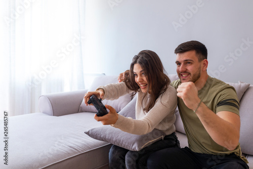  Young people having fun with new technology console online - Happiness and gaming concept. Photo of young couple playing video games at home . © Dragana Gordic