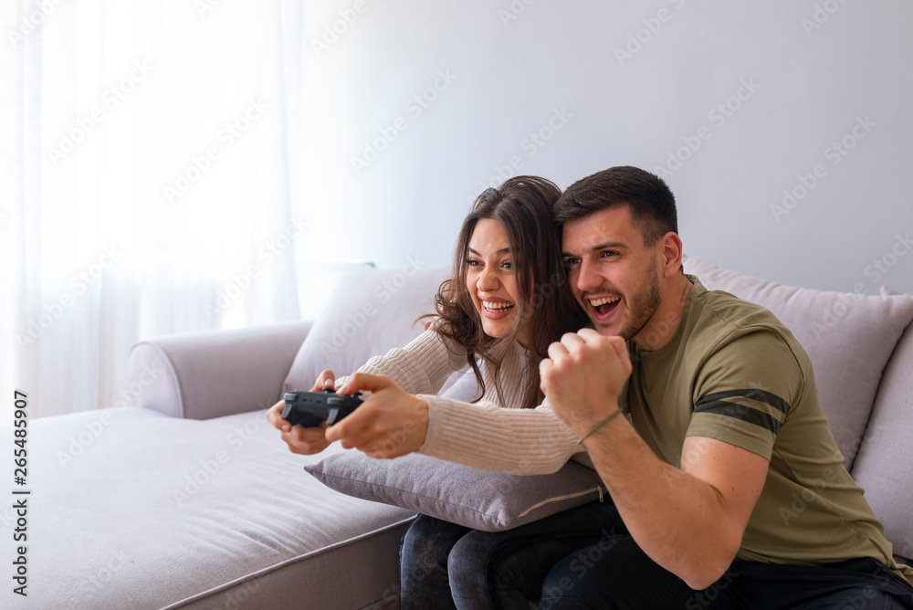 Young couple playing video games in their apartment. Did it! The best team ever. Beautiful lovers on a date indoors. Beautiful couple playing video games on console having fun. Young couple playing video games in their apartment. Did it! The best team ever. Beautiful lovers on a date indoors. Beautiful couple playing video games on console having fun.
