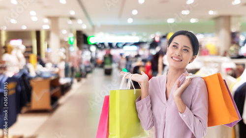 happy beautiful Asian women smile two hand holding shopping bags, copy space on shopping mall background, Annual discounted product price festival concept.