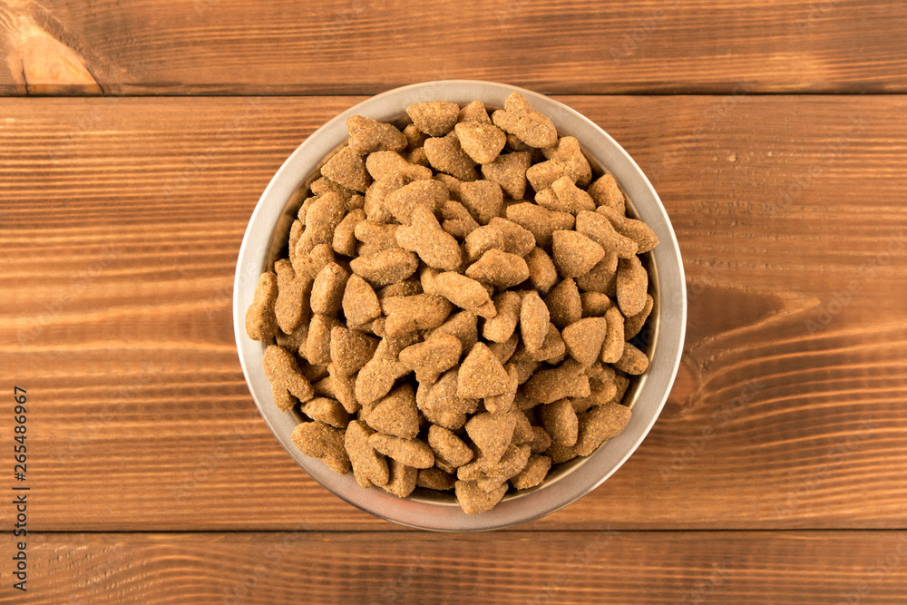 Bowl with dog food on a wooden table. Close up. Bowl with dog food on a wooden table. Close up.