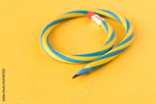 Flexible pencil . Isolated on yellow background. Bending pencil.