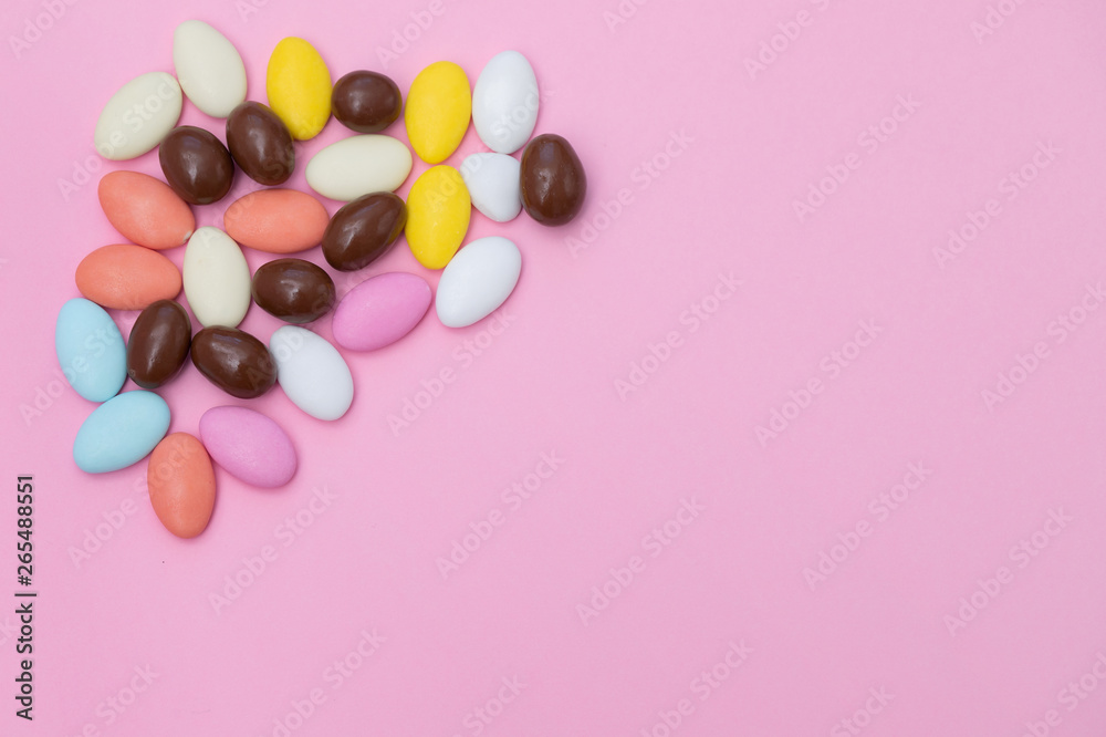 close up of chocolate egg and candy drops on pink background