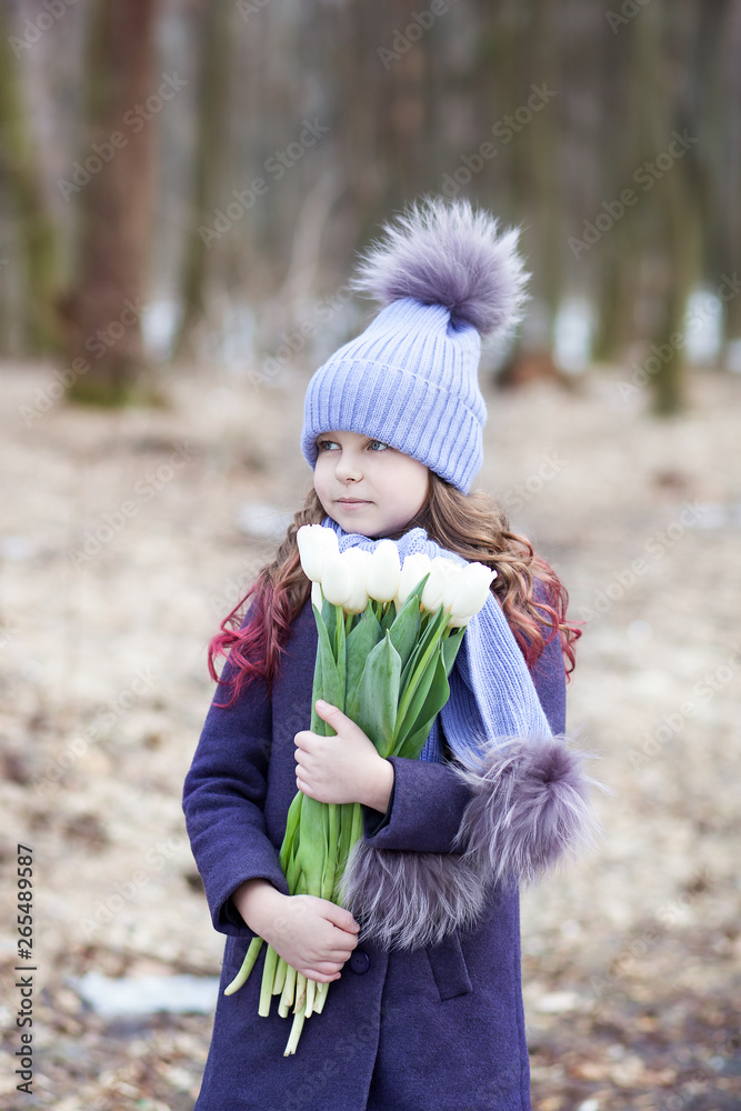 Cute little girl in the park with a bouquet of white tulips. Flowers as a gift for women's mother's day. March 8. Easter. Girl with a bouquet for happy mothers day. Makes a gift for your mom.