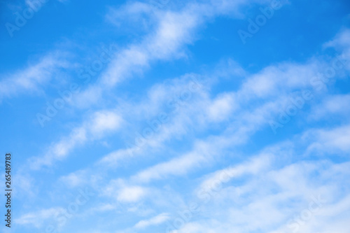 Cloudscape. Blue sky background with white clear  clouds. The texture of the sky with translucent light feathery clouds. Diagonal direction.