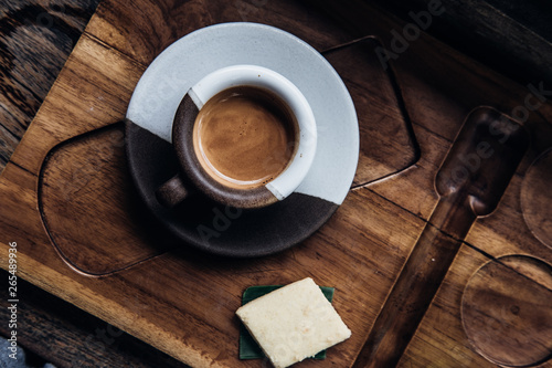 Overhead espresso coffee in a black and white ceramic cup on wooden table at coffee shop. Drink photography concept, minimalism, close up photo
