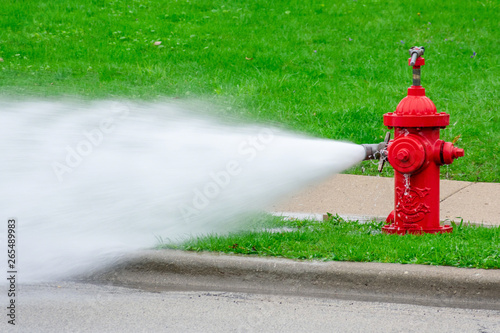 Closeup of red fire hydrant with high pressure spray photo