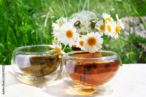 Two Cups of chamomile tea and a bouquet of chamomiles. Consept of alternative tea