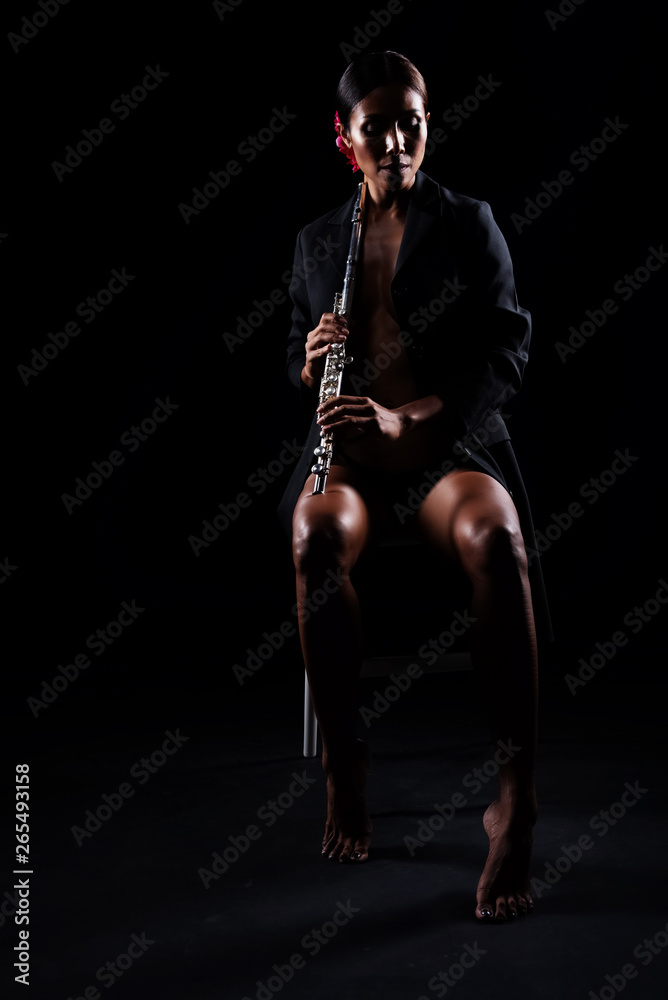 The beauty woman holding Flute in hand and playing music,sexy model posing with woodwind instrument,classic and art tone