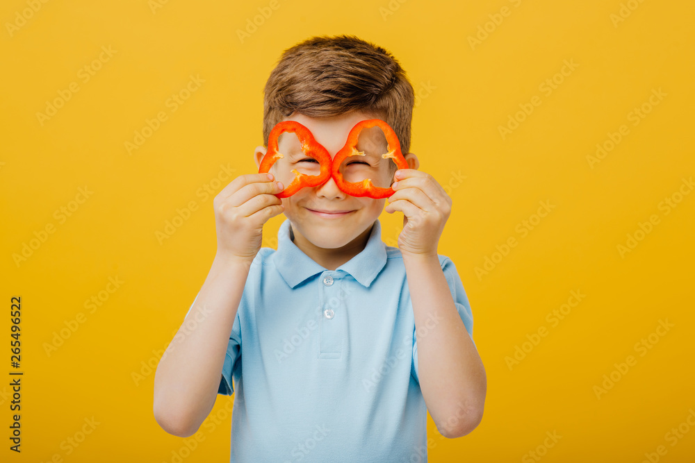 Φωτογραφία little boy has glasses pepper slices, look at the camera, in blue T-shirt, isola