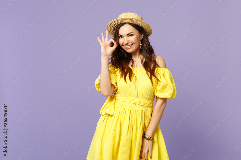 Portrait of stunning young woman in yellow dress, summer hat showing OK gesture looking camera isolated on pastel violet wall background. People sincere emotions lifestyle concept. Mock up copy space. Portrait of stunning young woman in yellow dress, summer hat showing OK gesture looking camera isolated on pastel violet wall background. People sincere emotions lifestyle concept. Mock up copy space.