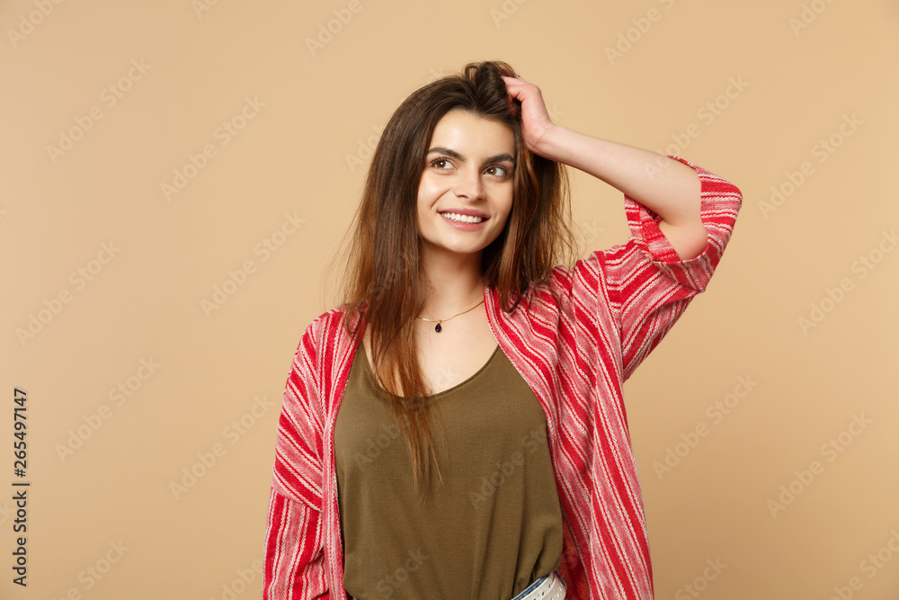Portrait of pensive smiling young woman in casual clothes looking aside, putting hand on head isolated on pastel beige wall background. People sincere emotions, lifestyle concept. Mock up copy space. Portrait of pensive smiling young woman in casual clothes looking aside, putting hand on head isolated on pastel beige wall background. People sincere emotions, lifestyle concept. Mock up copy space.